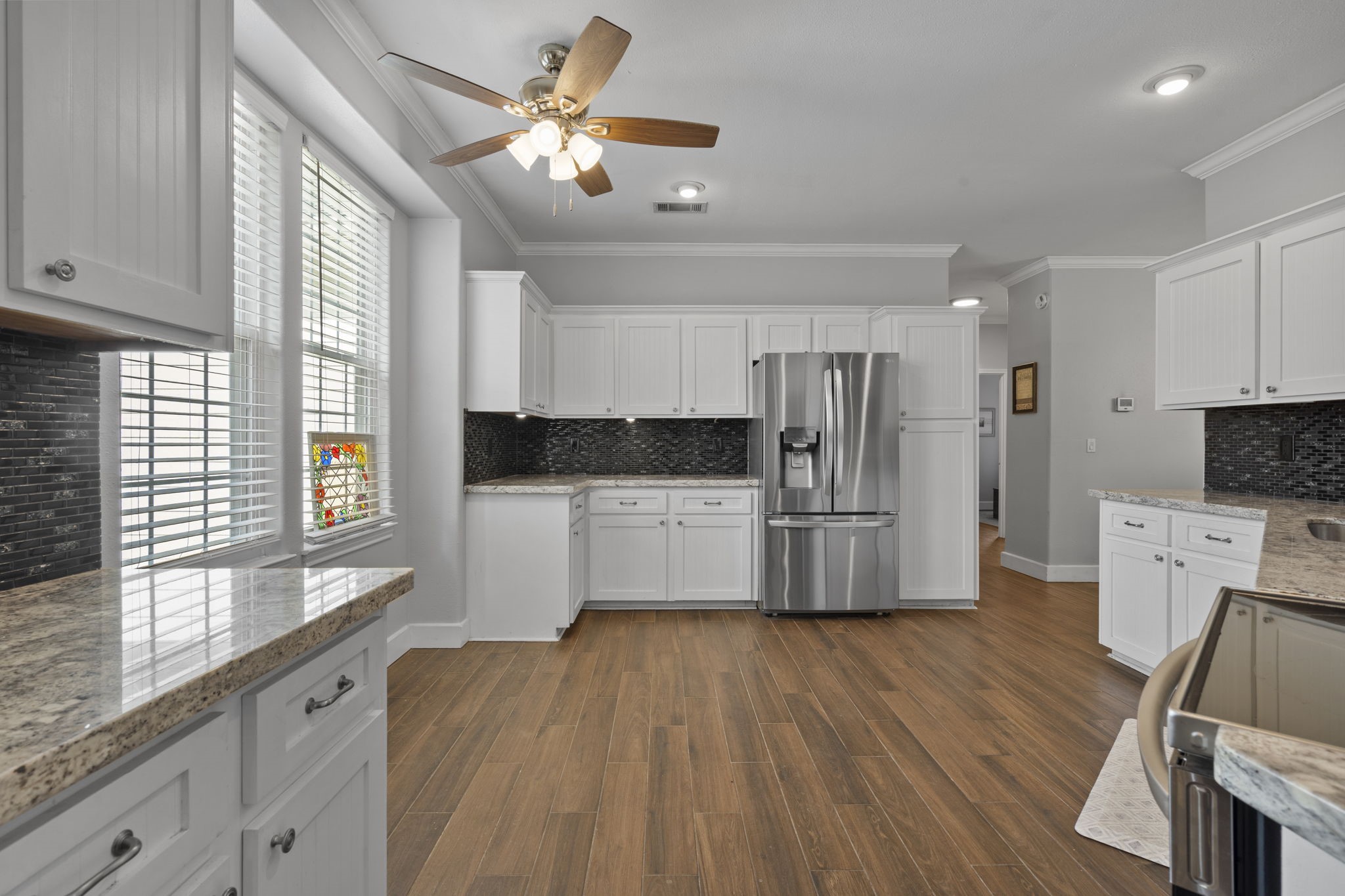 23200 Baneberry Road Magnolia, TX 77355 - Photo 16 of 39 a kitchen with granite countertop a refrigerator oven a sink dishwasher and white cabinets with wooden floor
