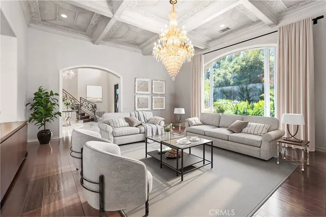 a living room with furniture a chandelier a large window and wooden floor