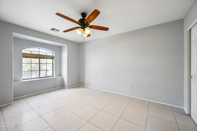 an empty room with chandelier fan and windows