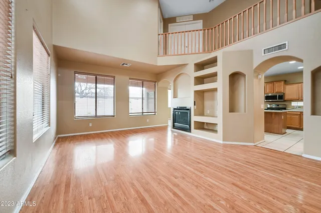 a view of a big room with wooden floor kitchen view and windows