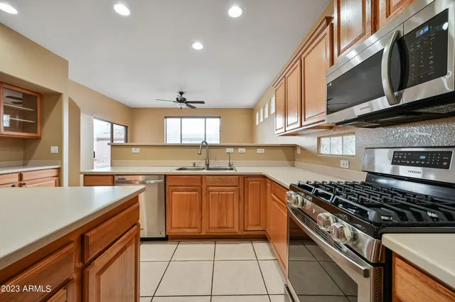 a large kitchen with stainless steel appliances granite countertop a stove top oven a sink a dining table and chairs