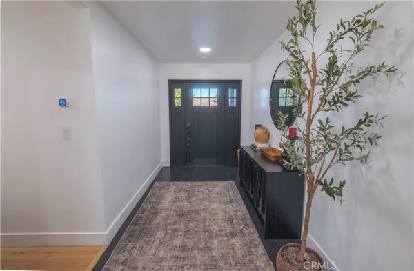 a living room with stainless steel appliances furniture a flat screen tv and kitchen view