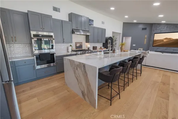 a kitchen with stainless steel appliances granite countertop a table chairs sink refrigerator and cabinets