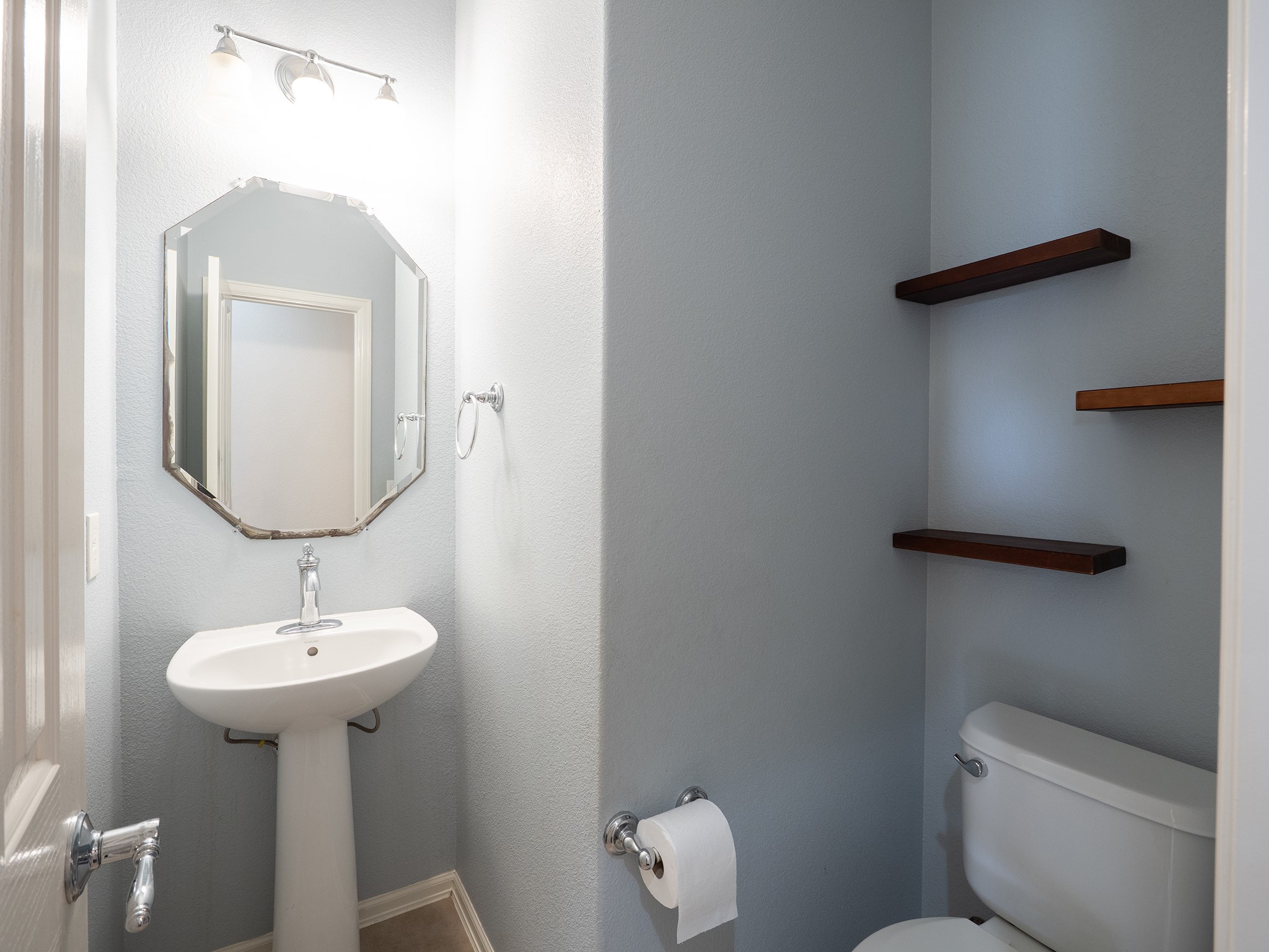 572 Big Meadow Road Austin, TX 78737 - Photo 23 of 32 A well-lit half bathroom offers a sleek pedestal sink and floating corner shelves for convenience.