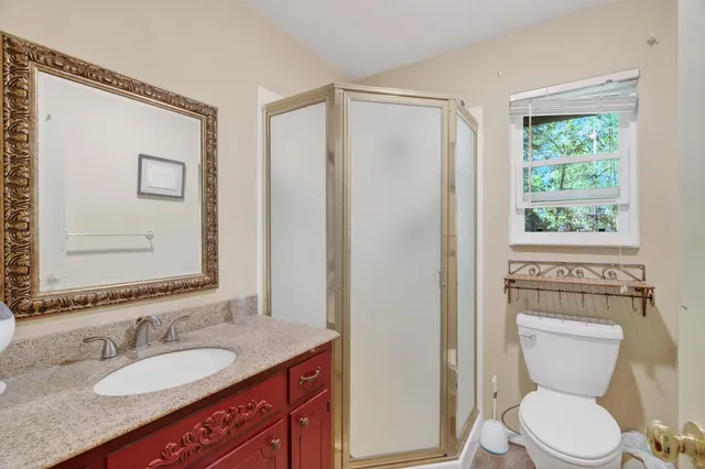 a bathroom with a granite countertop toilet sink and mirror
