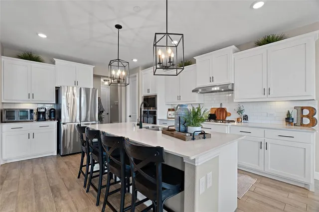a kitchen with stainless steel appliances kitchen island granite countertop a table chairs and white cabinets