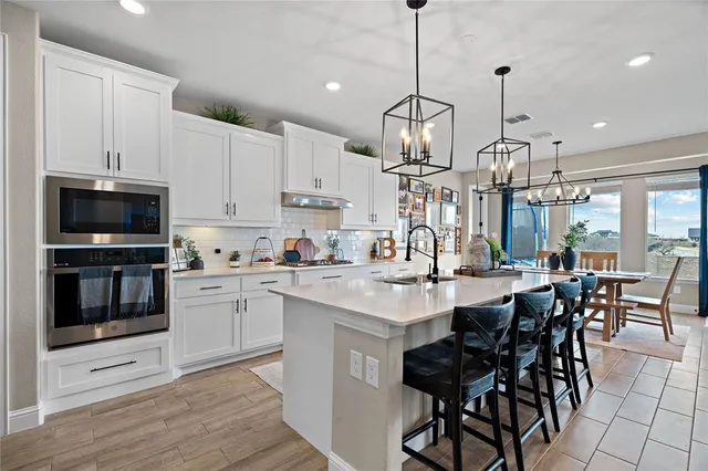 a kitchen with stainless steel appliances kitchen island granite countertop a sink a stove a dining table and chairs