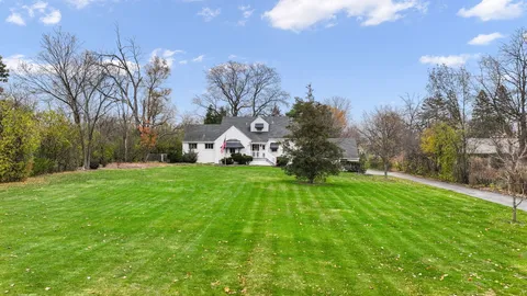 a view of a house with a big yard and large trees