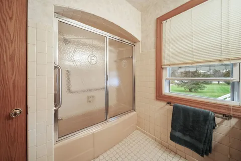 a bathroom with a glass shower door and a window