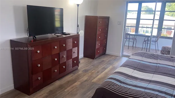 a bedroom with a bed and a flat tv screen on dresser