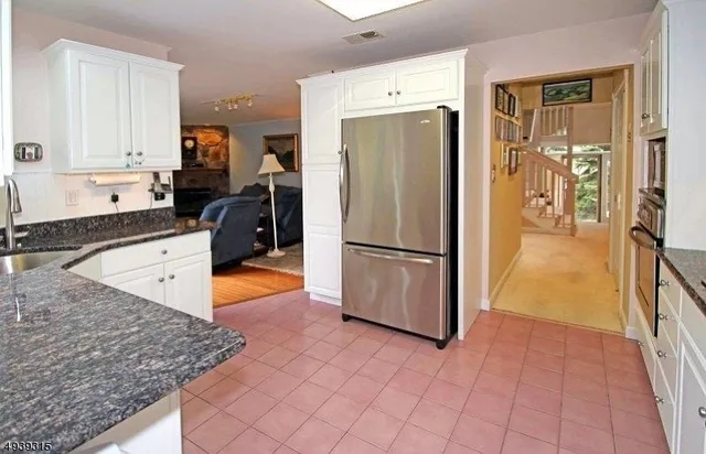 a kitchen with stainless steel appliances granite countertop a refrigerator a stove and a sink