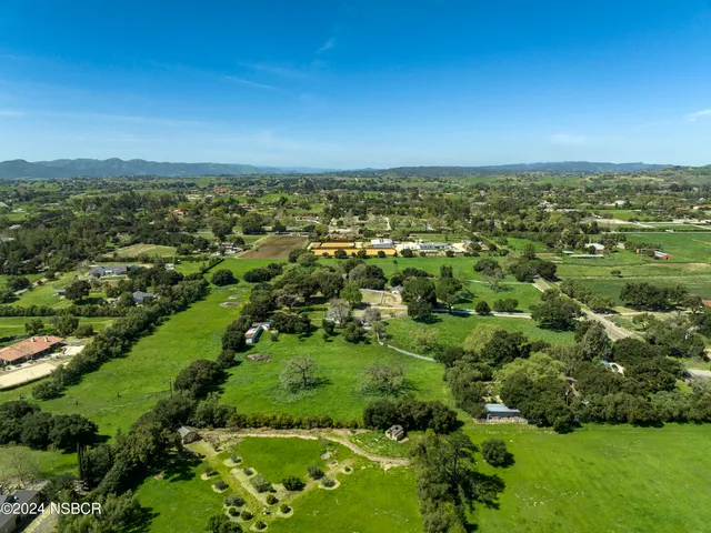 an aerial view of residential houses with outdoor space and trees