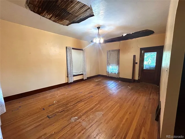 a view of an empty room with wooden floor and a ceiling fan
