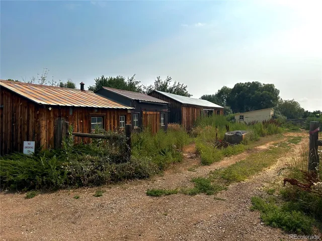 a view of a house with a yard and table and chairs under an umbrella