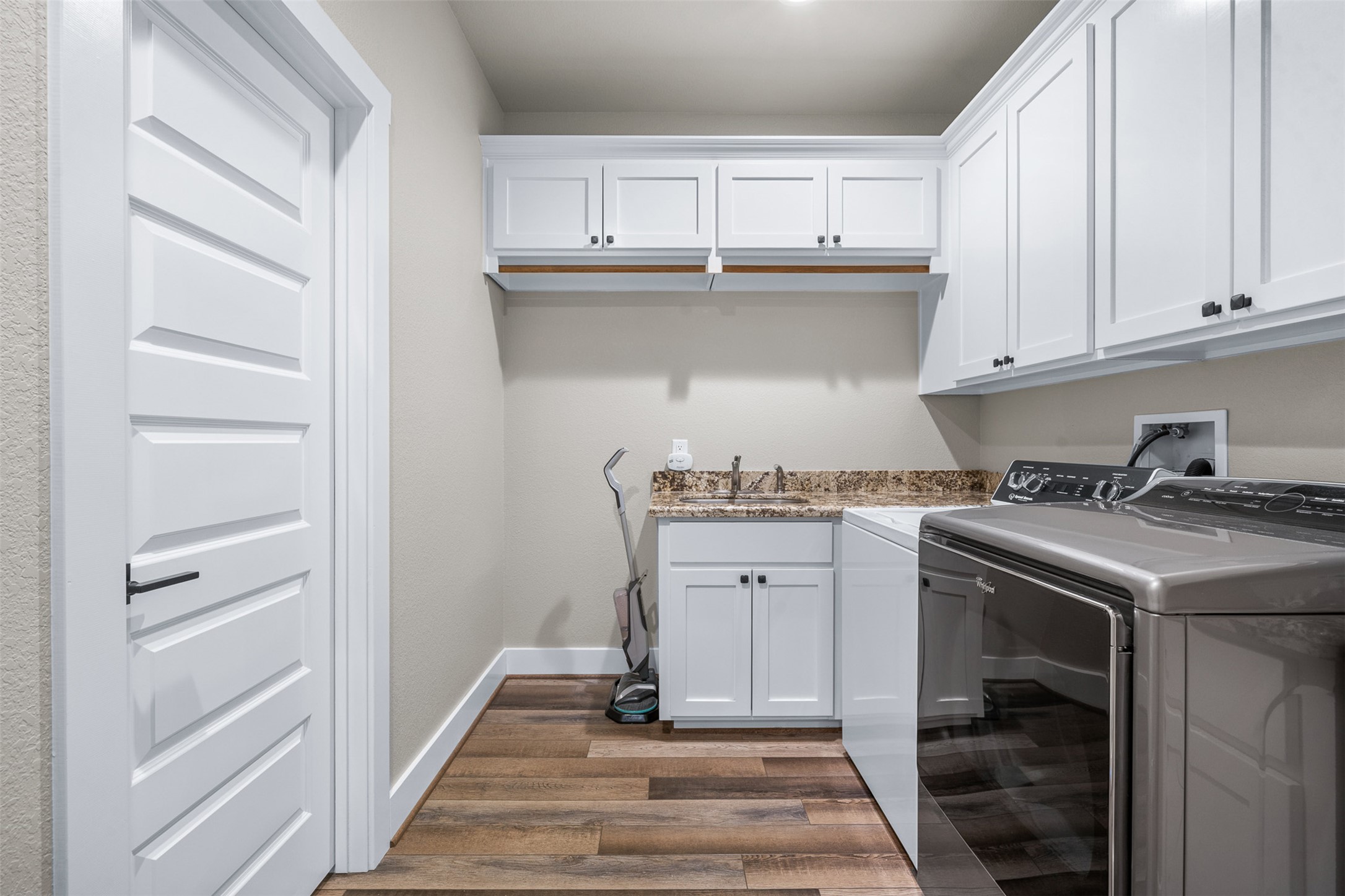 1306 22 Hills Road Gause, TX 77857 - Photo 7 of 40 Dedicated utility space featuring wood-finish flooring and a five-panel interior door
