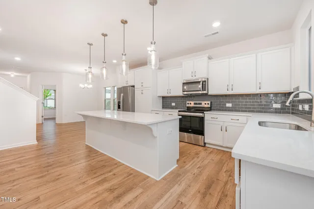 a large kitchen with stainless steel appliances kitchen island granite countertop a stove a sink a microwave and white cabinets