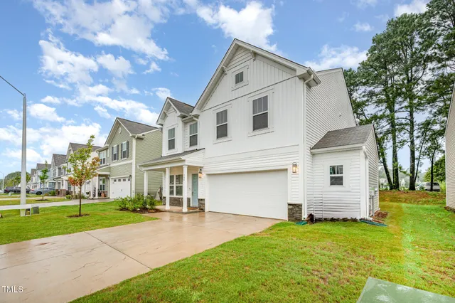 a view of a white house next to a yard with big trees