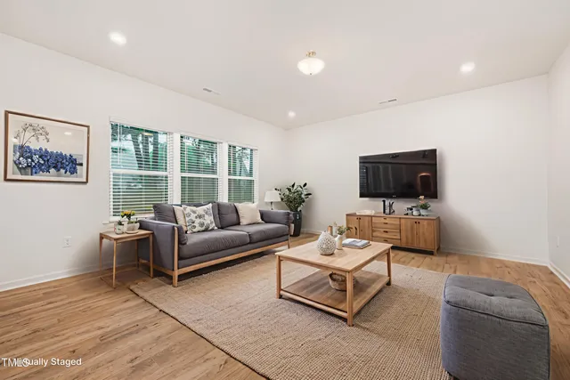 a living room with furniture a flat screen tv and a window