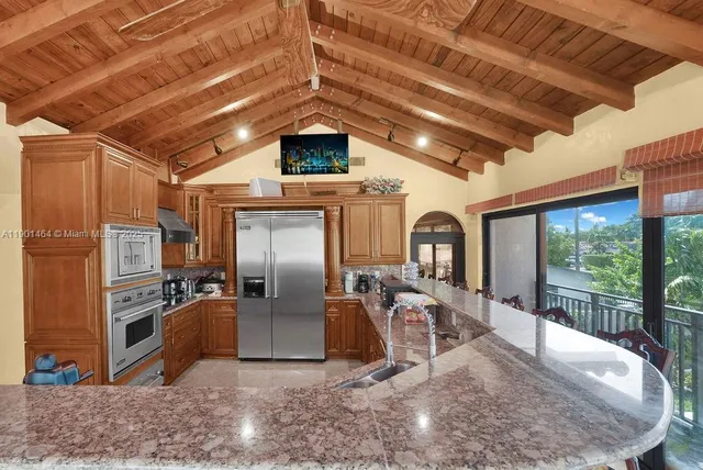 a view of a kitchen with stainless steel appliances granite countertop a stove top oven a sink and a refrigerator