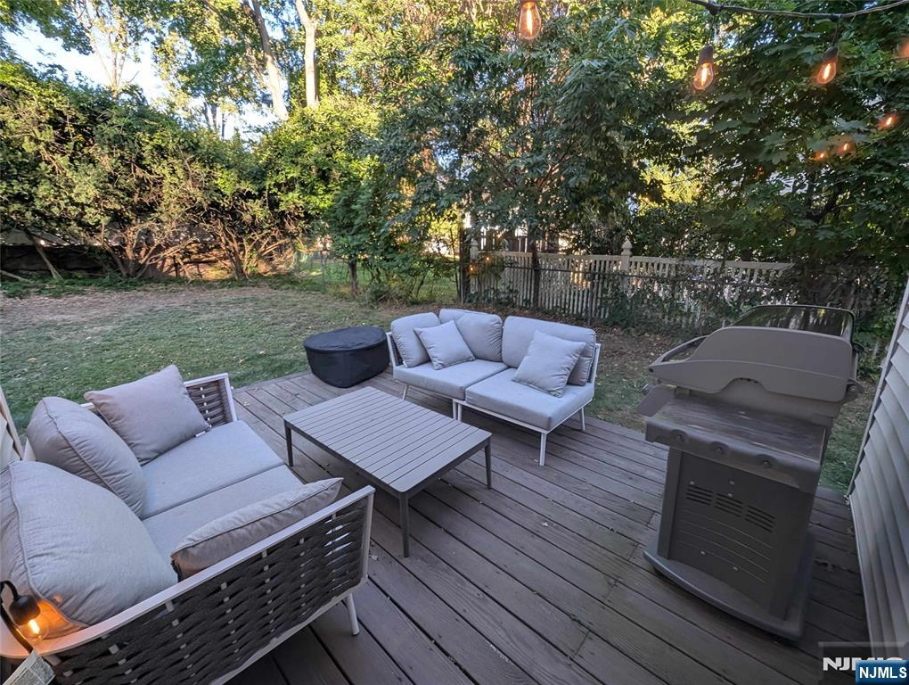 99 Park Avenue Cresskill, NJ 07626 - Photo 20 of 46 a view of a patio with couches and a table and chairs with wooden floor and fence