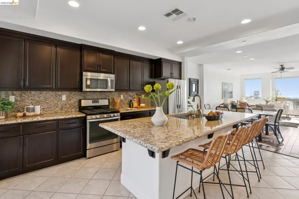 a kitchen with stainless steel appliances granite countertop a stove top oven a sink a dining table and chairs