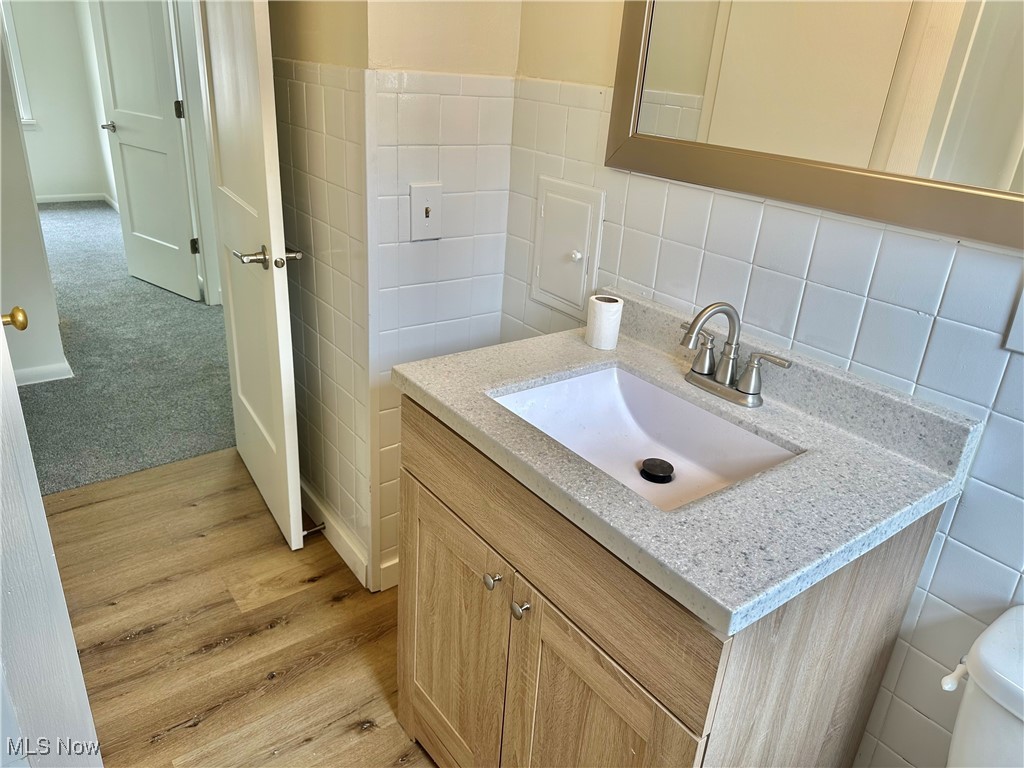4366 Roadoan Road Brooklyn, OH 44144 - Photo 14 of 27 Half bath with tile walls, vanity, wood finished floors, and toilet