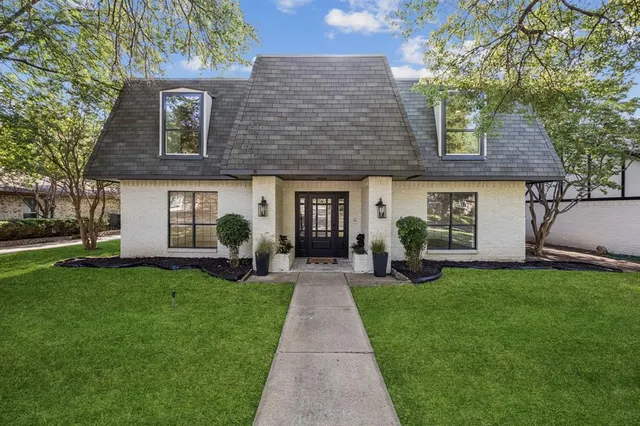 a front view of a house with a garden and trees