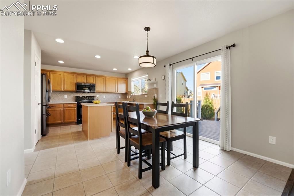 8318 Shadow Run Lane Fountain, CO 80817 - Photo 11 of 50 a kitchen with stainless steel appliances granite countertop a dining table chairs and white cabinets