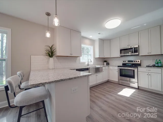 a kitchen with granite countertop a stove a sink and a refrigerator