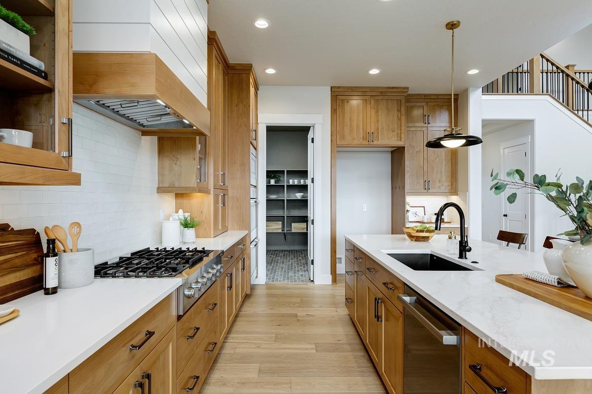 6774 Saddle Bred Way Star, ID 83669 - Photo 8 of 41 Kitchen featuring brown cabinets, recessed lighting, appliances with stainless steel finishes, pendant lighting, and light stone counters