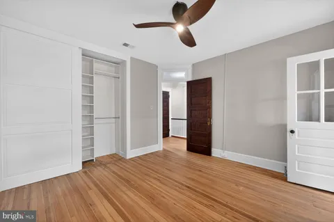 a view of empty room with wooden floor and fan