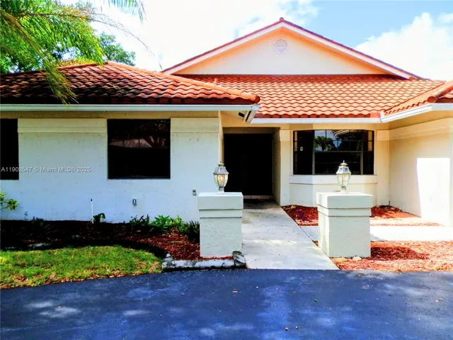 a front view of a house with a yard and potted plants