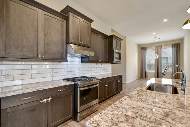 a kitchen with stainless steel appliances granite countertop a sink stove and refrigerator