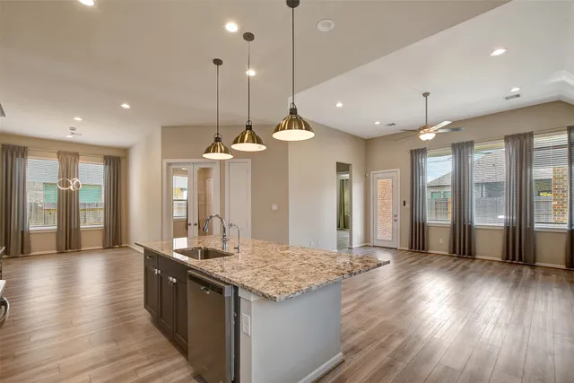 a large kitchen with granite countertop a large kitchen island white cabinetry and wooden floor