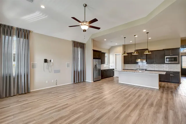 a large kitchen with stainless steel appliances kitchen island a large counter top and wooden floors