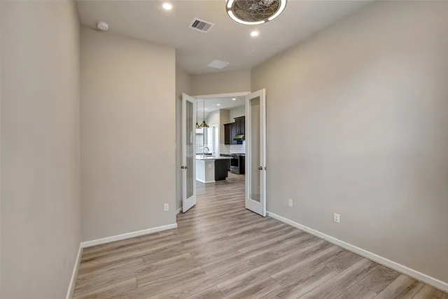 a view of a hallway with wooden floor and a kitchen