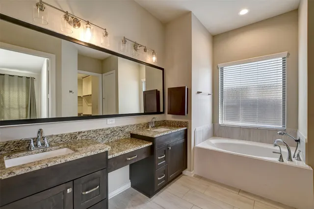 a bathroom with a granite countertop bathtub a double vanity sink and mirror