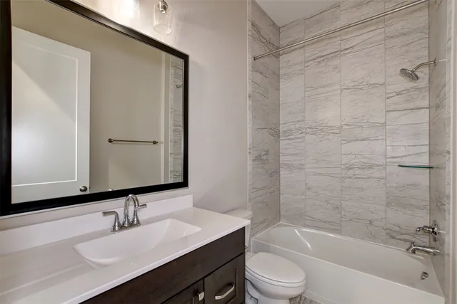 a bathroom with a bathtub shower sink vanity and toilet