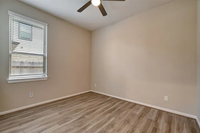 an empty room with a window and a ceiling fan