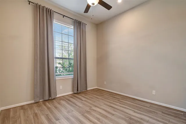 an empty room with a window and a ceiling fan