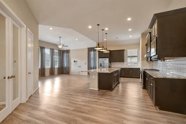 a view of kitchen with stainless steel appliances refrigerator stove microwave and wooden floor