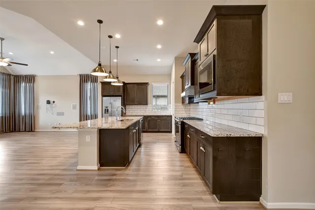 a large kitchen with stainless steel appliances kitchen island granite countertop a large counter top and stove