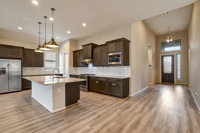 a large kitchen with stainless steel appliances kitchen island granite countertop a stove a sink dishwasher and a oven with wooden floor