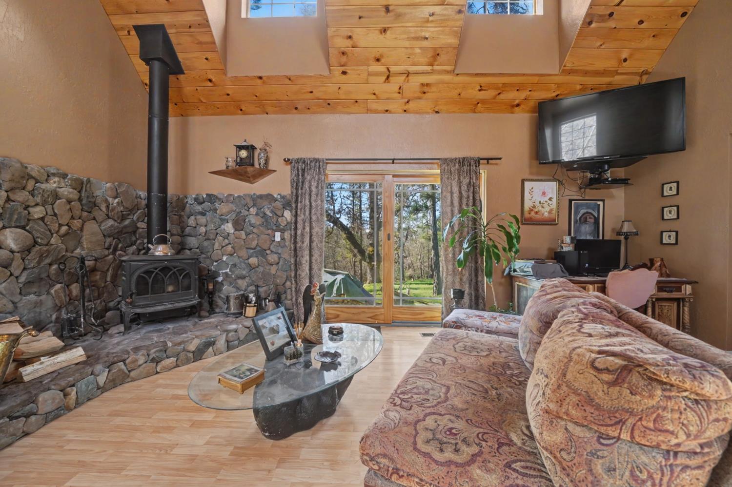6145 Swiss Ranch Road Mountain Ranch, CA 95246 - Photo 37 of 84 a living room with furniture a flat screen tv and a floor to ceiling window
