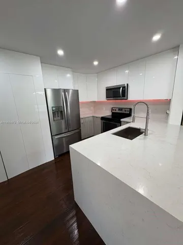 a large white kitchen with a refrigerator a microwave a sink and a stove
