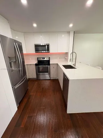 a kitchen with stainless steel appliances a refrigerator a sink wooden floor and cabinets