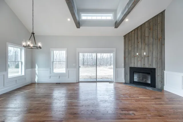 a view of an empty room with wooden floor fireplace and a window