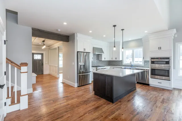 a large kitchen with stainless steel appliances granite countertop a stove a refrigerator and a wooden floors