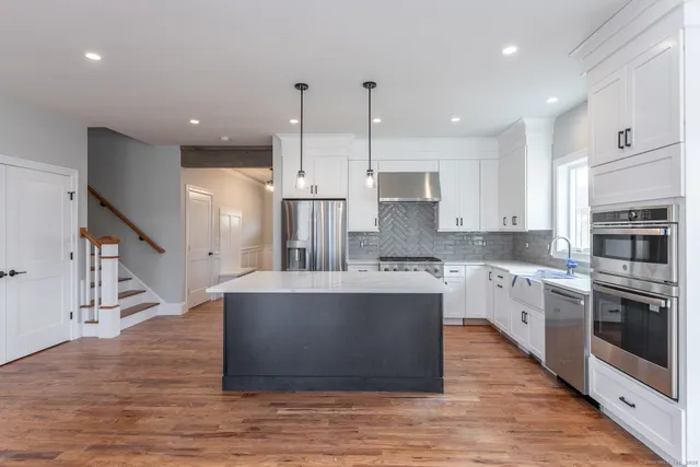 a large kitchen with stainless steel appliances kitchen island granite countertop a large counter top and a stove top oven