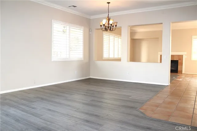 an empty room with wooden floor chandelier and windows